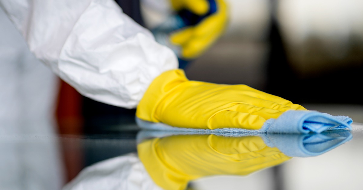 A person in PPE disinfecting and wiping down a surface.