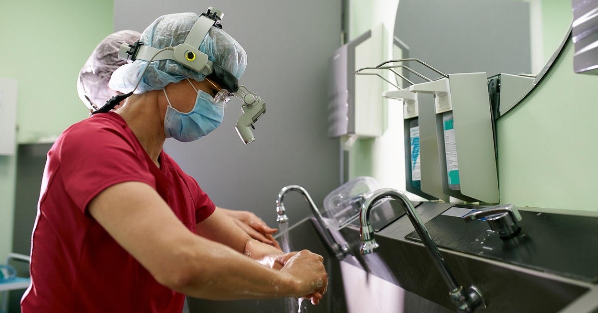 A surgeon washing their hands in a hospital sink, leading to the build up of biofilm and infectious diseases.