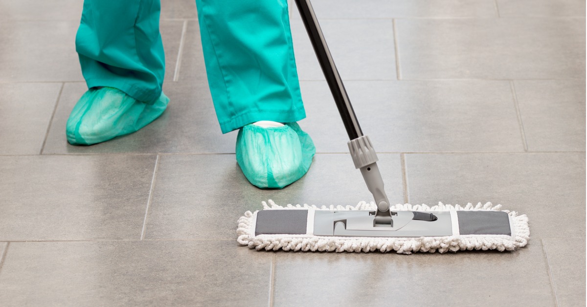 Health care worker using disposable shoe covers while mopping the floor.