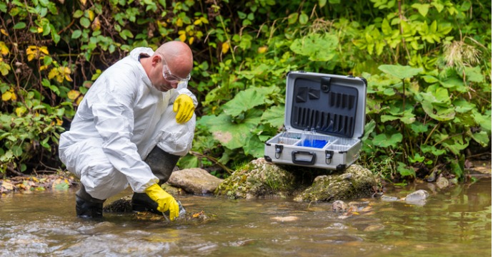 scientist grabbing a water sample from wastewater to detect covid