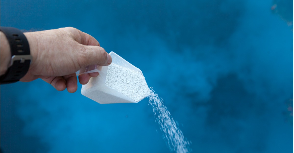 Man pouring chlorine into water during chlorination.