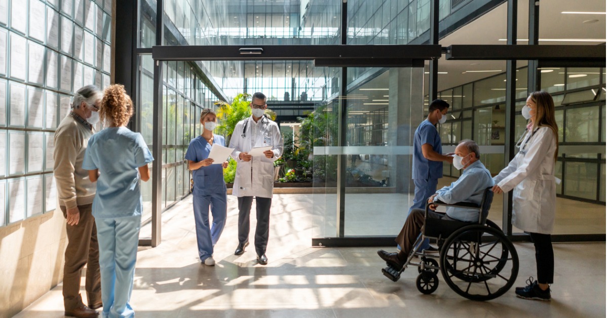 Patrons walking in and out of a healthcare facility alongside doctors and nurses.