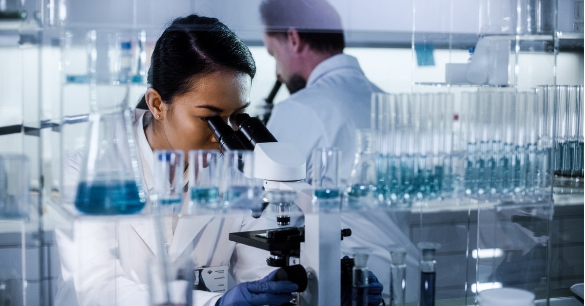 Scientists using microscopes while testing medicines for approval in line with TGA Australia standards.