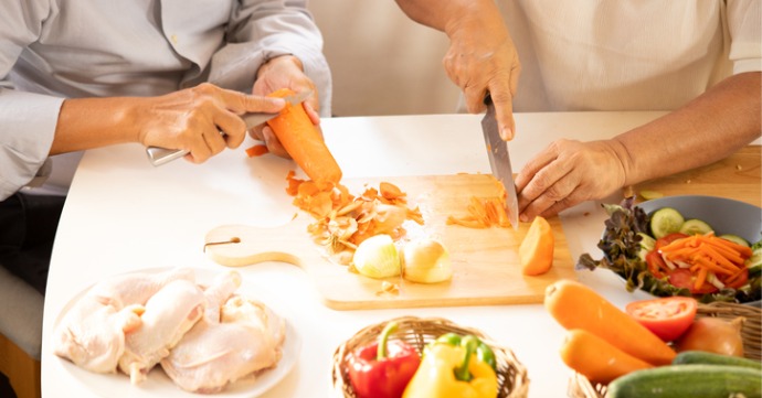 two people cutting and prepping raw food in the kitchen