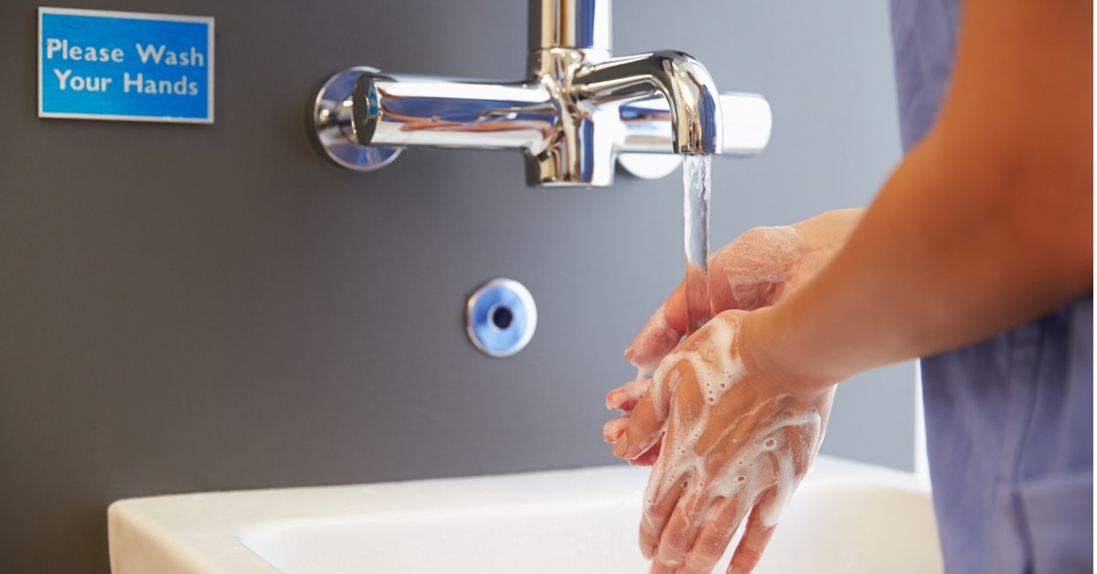 Woman washing her hands with soap in the sink while in a health care setting.